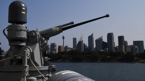 One of the guns aboard the NUSHIP Hobart (III), the first of 3 Hobart Class Guided Missile Destroyers, points out over the city skyline while the ship is moored at Fleet Base East in Sydney.