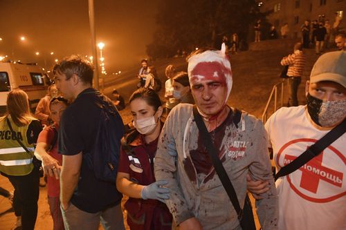 People help a wounded man during clashes with police after the Belarusian presidential election in Minsk, Belarus