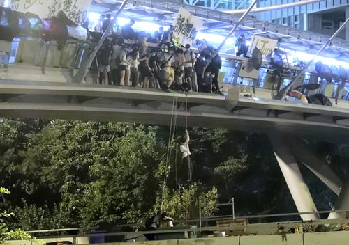 Protesters use a rope to lower themselves from a pedestrian bridge to waiting motorbikes in order to escape from Hong Kong Polytechnic University and the police in Hong Kong.