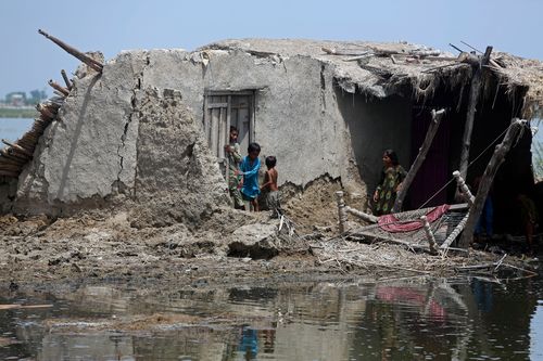 Children stand in front of their flooded home after monsoon rains, in the Qambar Shahdadkot district of Sindh Province