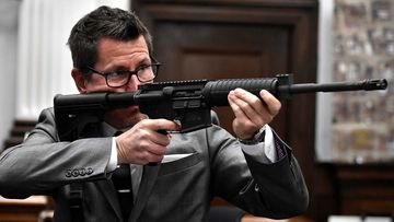 Prosecutor Thomas Binger points a rifle during his closing argumentsin the Rittenhouse trial.