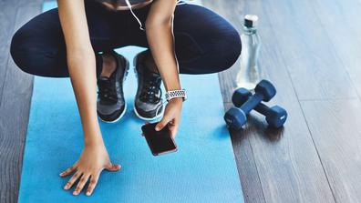 Woman working out with phone and dumbbells