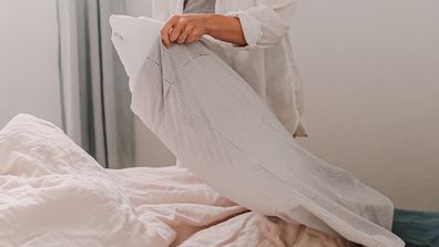 Woman making her bed changing pillowcase