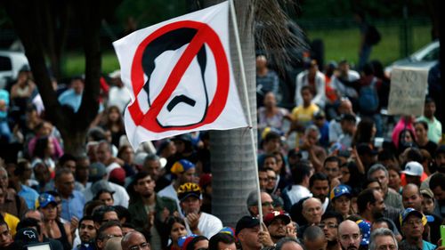 An anti-government demonstrator waves a flag against Venezuela's President Nicolas Maduro during a vigil in honor of those who have been killed during clashes between security forces and demonstrators (AP Photo/Ariana Cubillos).