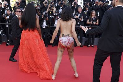 A protestor that was wearing body paint on her front that read "Stop Raping Us" in the color of the Ukrainian flag appears at the premiere of the film 'Three Thousand Years of Longing' at the 75th international film festival, Cannes, southern France, Friday, May 20, 2022. 