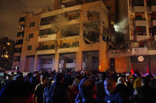 People gather outside a damaged building following a massive explosion in the southern Beirut 