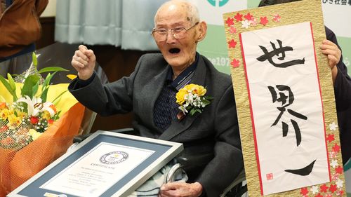 Chitetsu Watanabe poses next to calligraphy reading in Japanese 'World Number One' after he was awarded as the world's oldest living male in Joetsu, Niigata.