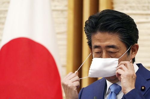 Then Japanese Prime Minister Shinzo Abe removes a face mask before speaking at a press conference at his official residence in Tokyo May 4, 2020 