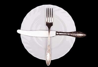 Crossed utensils on plate (Getty)