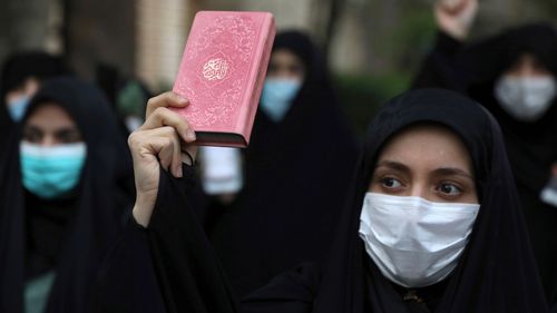 A protester holds a copy of the Quran, the Muslims holy book, during a demonstration to condemn planned Koran burnings by a right-wing group in Sweden, in front of the Swedish Embassy in Tehran, Iran.