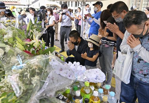 People pray at a makeshift memorial near the scene where the former Prime Minister Shinzo Abe was shot while delivering his speech to support the Liberal Democratic Party's candidate during an election campaign in Nara, Saturday, July 9, 2022.  