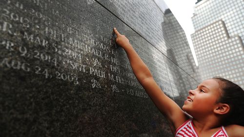 Gabriella Ortiz points to the name of her grandfather, fallen New York City police officer Edwin Ortiz at a wall commemorating officers who died during 9/11. (AFP)