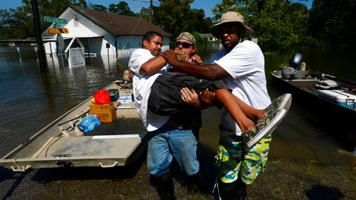 Chris McCarty and Mike Taylor help carry Quintin Sanders, who has cerebral palsy, off a rescue boat in the north end of Beaumont, Texas. (AP)