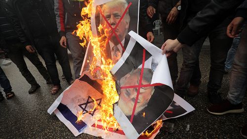 Posters of US President Donald Trump and Israeli Prime Minister Benjamin Netanyahu set alight by protestors in Gaza. (AAP)