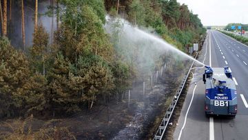 A police water cannon works to extinguish a forest fire that has broken out in the wood within the Potsdam and Fichtenwalde triangles. (AAP)