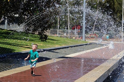 Seven-year-old Tom Ashton gets relief from the heat at a water fountain at Sydney Olympic Park. (AAP)