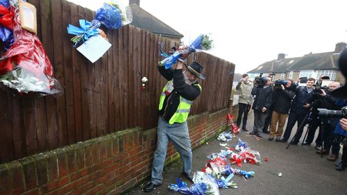 Iain Gordon pulls the flowers down from a fence opposite the house of Richard Osborn-Brooks in South Park Crescent in Hither Green, London. (AAP)