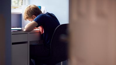 Boy leaning over desk.