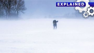 A man walks across a snow-covered field.