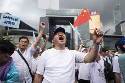 A pro police demonstrator chants slogans and waves a Chinese flag during the rally in support of the police. 