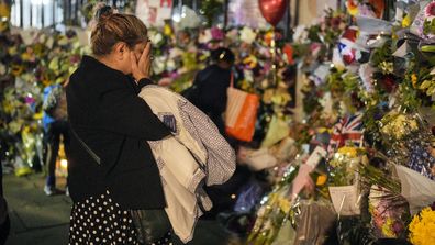 A woman prays beside thousands of flowers in front of Buckingham Palace in London, Friday, Sept. 9, 2022. Queen Elizabeth II, Britain's longest-reigning monarch and a rock of stability across much of a turbulent century, died Thursday Sept. 8, 2022, after 70 years on the throne. She was 96. (AP Photo/Martin Meissner)