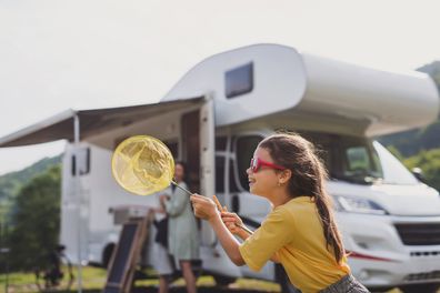 Young girl on a camping trip. Young girl blowing balloon. Kids camping. 