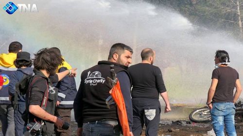 Rescue and media personnel at the scene of a car bomb attack that targeted buses evacuating civilians west of Aleppo. (AAP) 