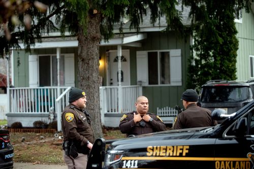 A photo taken December 3 shows three Oakland County Sheriff's deputies outside the Crumbley residence while they were looking for James and Jennifer Crumbley. They were later found inside a business venue.