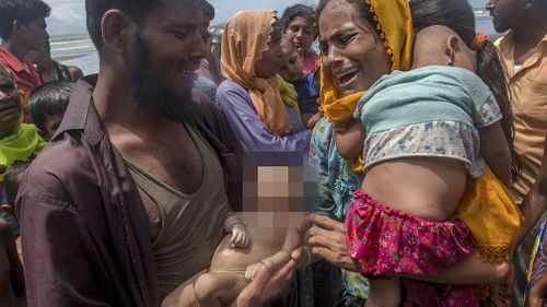 Naseer Ud Din holds his infant son Abdul Masood, who drowned when the boat they were travelling in capsized just before reaching the shore, as his wife Hanida Begum cries upon reaching the Bay of Bengal shore in Shah Porir Dwip. (AP)