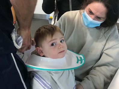 Baby with toilet seat stuck around his neck looking at the camera