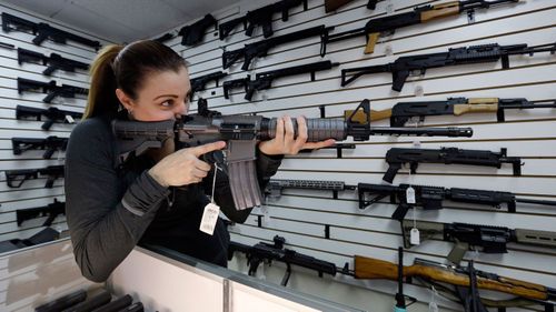 Gun shop owner Tiffany Teasdale-Causer points a Ruger AR-15 semi-automatic rifle