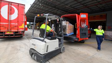 Workers pack Australia Post delivery trucks and vans