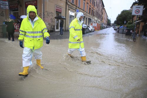 People crosses a flooded street in Bologna, Italy, Tuesday, May 16, 2023. 