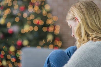 Woman sad at Christmas. Woman and Christmas tree. Sad woman.