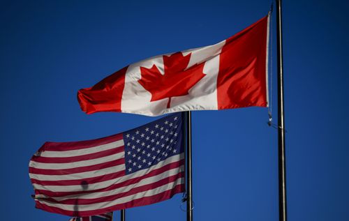 The flags of Canada and the United States fly outside a hotel in downtown Ottawa, on Saturday, Feb. 1, 2025. (Justin Tang/The Canadian Press via AP)