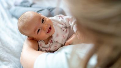 Mother carrying her smiling baby girl at home