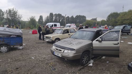 Police officers and medical workers work near damaged cars after a Russian rocket attack in Zaporizhzhia, Ukraine, Friday, Sept. 30, 2022. 