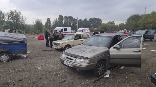 Des policiers et des travailleurs médicaux travaillent à proximité de voitures endommagées après une attaque à la roquette russe à Zaporizhzhia, en Ukraine, le vendredi 30 septembre 2022. 