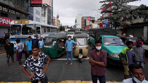 People wait as protesters demanding fuel block traffic near a fuel station in Colombo, Sri Lanka.