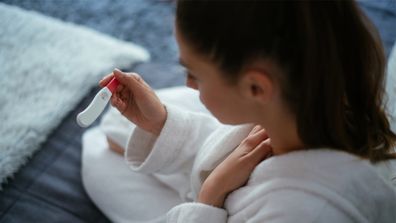 Woman looking at pregnancy test in shock.