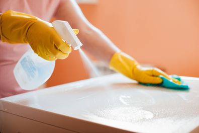 woman doing chores in bathroom at home, cleaning surfaces sink and faucet with spray detergent suds sponge. 