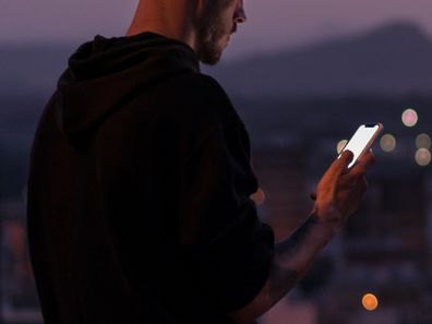 Man on smart phone outdoors at night