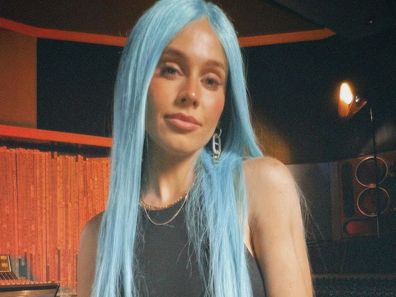 DJ Tigerlily poses in her signature blue wig in a recording studio.