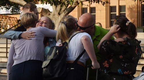 People embrace returning family members in Circular Quay.