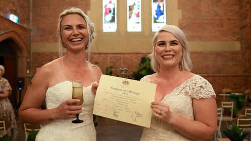 Sarah Turnbull (left) and Rebecca Hickson pose for a photograph with their Certificate of Marriage. (AAP)