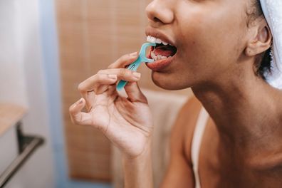 Stock photo of a woman flossing her teeth.