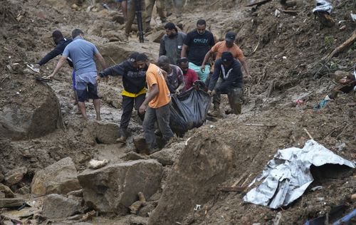 Residents and volunteers remove the body of a landslide victim in Petropolis, Brazil, Wednesday, Feb. 16, 2022. 