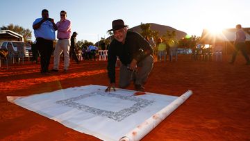 Noel Pearson signs the canvas where the Uluru Statement from the Heart will be painted on, in this photo from 2017.