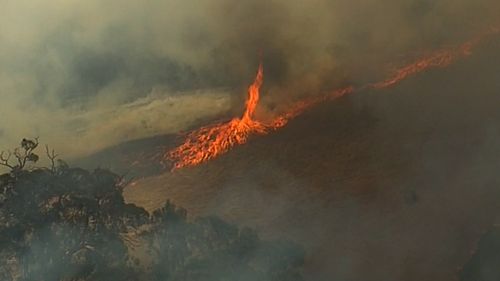 A bushfire blackening Adelaide Hills has been downgraded to the lowest warning level as firefighters work around the clock to extinguish the blaze.