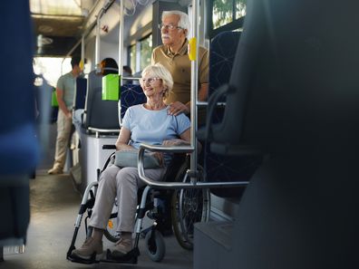 Happy disabled senior woman in a wheelchair and her husband traveling by bus.